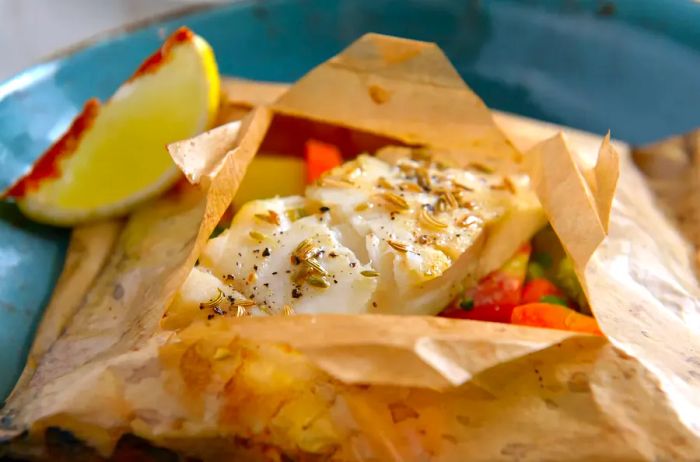 White fish fillet baked in parchment paper with vegetables