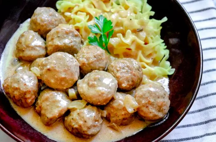 Overhead view of a bowl of homemade Easy Slow Cooker Swedish Meatballs served with egg noodles