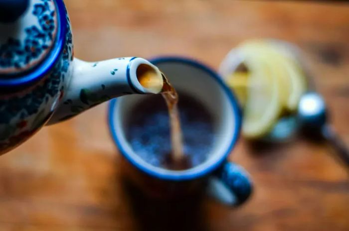 Close-up of a kettle pouring tea into a cup