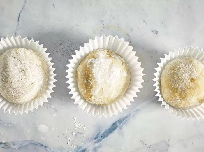 Three mochi balls sitting in paper muffin liners.