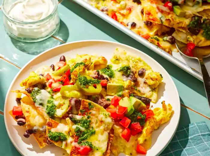 A plate of Breakfast Nachos topped with Chimichurri and pickled jalapeños