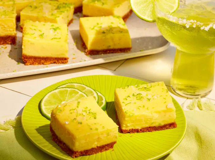 Margarita Bars garnished with a sprinkle of lime zest and fresh lime slices on a green plate