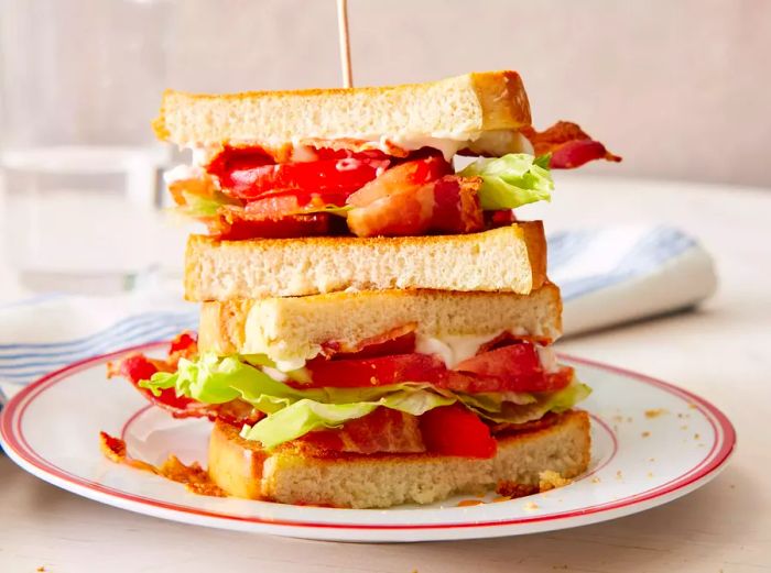 Two halves of a BLT sandwich stacked on top of each other on a plate