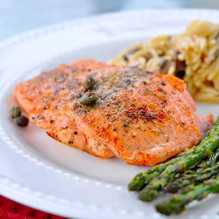 A close-up of a perfectly pan-seared salmon fillet served with a side of tender asparagus.