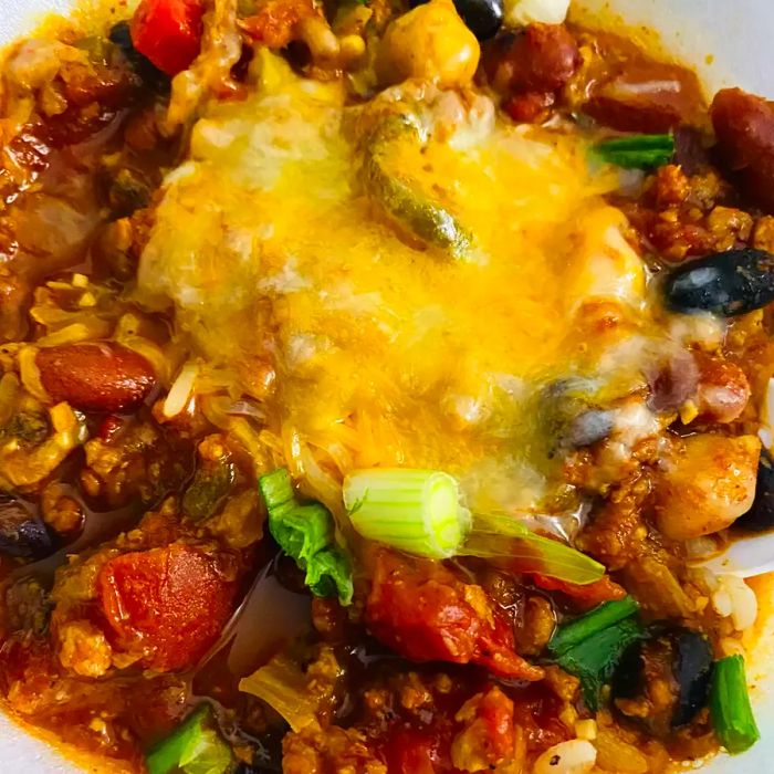 A close-up shot of vegetarian chili in a bowl, topped with melted cheese.