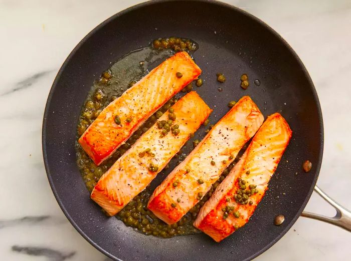 Salmon fillets topped with capers, salt, and freshly ground pepper.