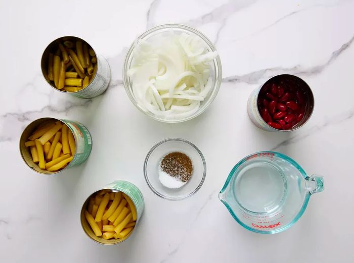 An overhead view of the three bean salad ingredients displayed in various bowls and containers.