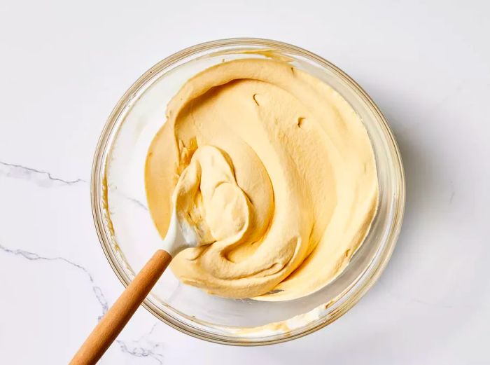 Dulce De Leche Ice Cream in a glass bowl with a spoon beside it