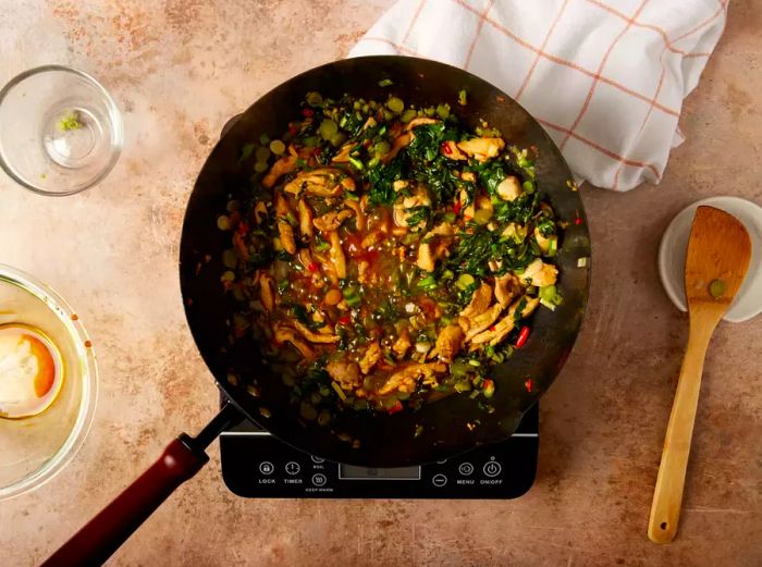 Vegetables, sliced chicken, and sauce gently simmering in a wok.