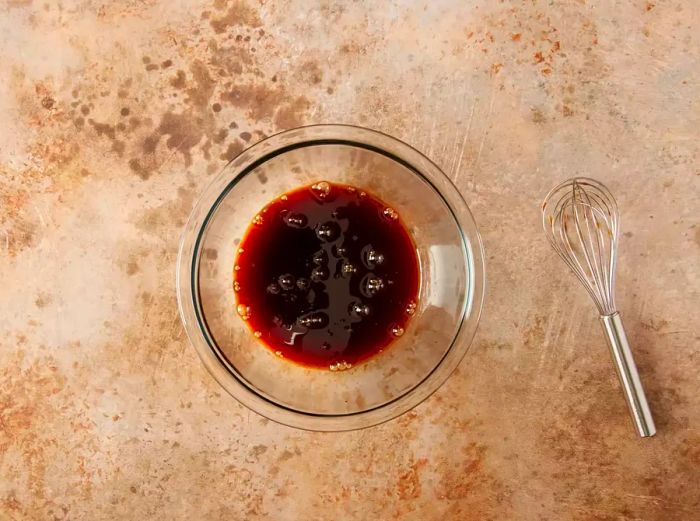 Oyster sauce, soy sauce, fish sauce, maple syrup, sugar, and water combined in a small bowl.