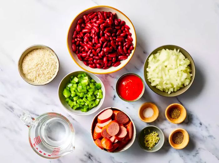 Red beans and rice ingredients arranged on a marble countertop.