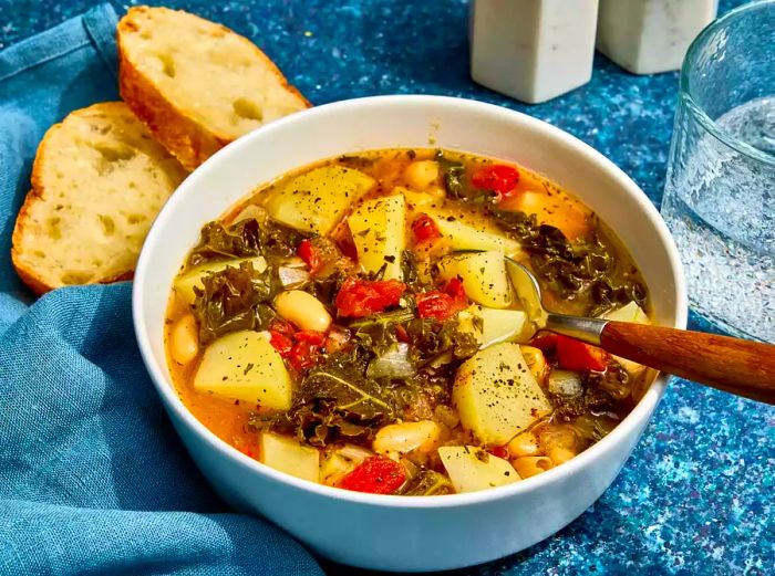 A bowl of hearty vegetarian kale soup served with two slices of crispy toasted bread