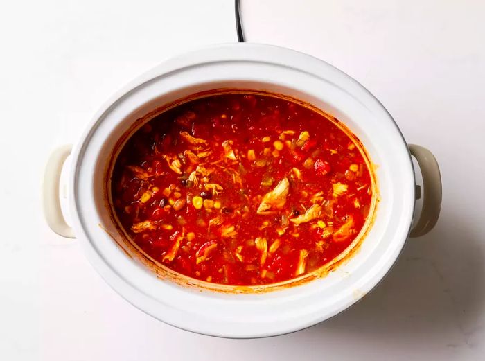 A slow cooker filled with shredded chicken taco soup.