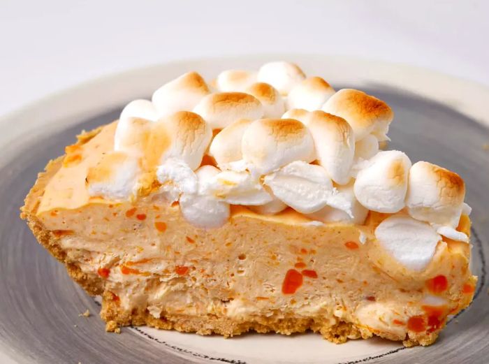 A slice of sweet potato casserole cheesecake topped with marshmallows and a graham cracker crust.