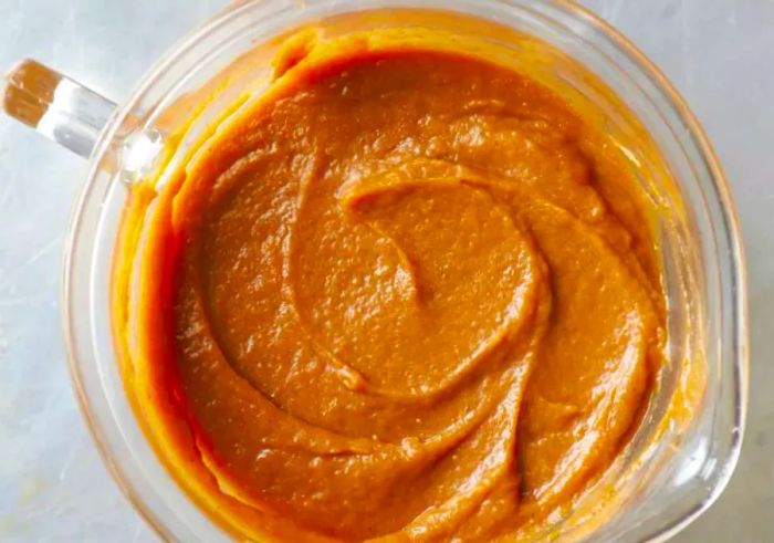 An overhead shot of pumpkin purée in a glass measuring cup.