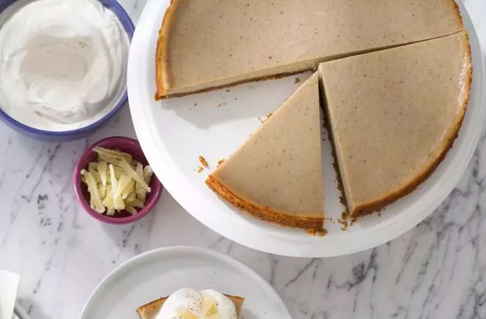 A chai spice cheesecake placed on a countertop, with a slice served on a plate.