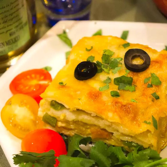 A hearty serving of a tortilla casserole, topped with melted cheese and sliced black olives.