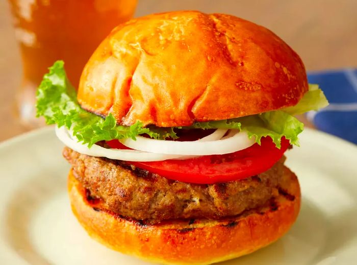 Close-up view of a perfectly assembled basic burger with lettuce, tomato, and onions, served on a plate