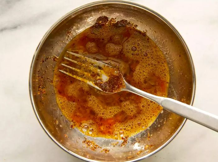 Top-down view of a mixing bowl filled with wet ingredients for a burger recipe