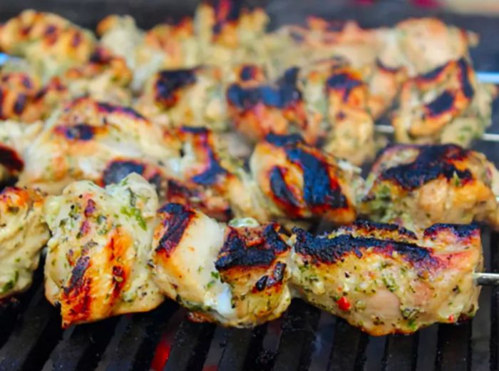 closeup of skewers loaded with herb-marinated chicken pieces grilling to perfection (Chef John's Grilled Chicken Spiedies)