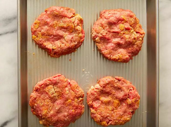 Top-down view of formed beef patties placed on a baking sheet