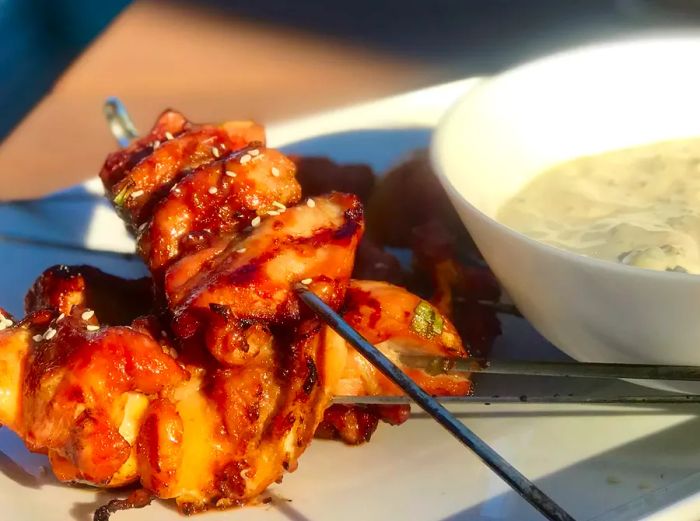 close-up of two of Chef John's Grilled Chicken Teriyaki Skewers with Miso Ranch on the side