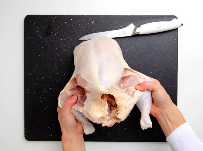 Removing the thighs from the whole chicken