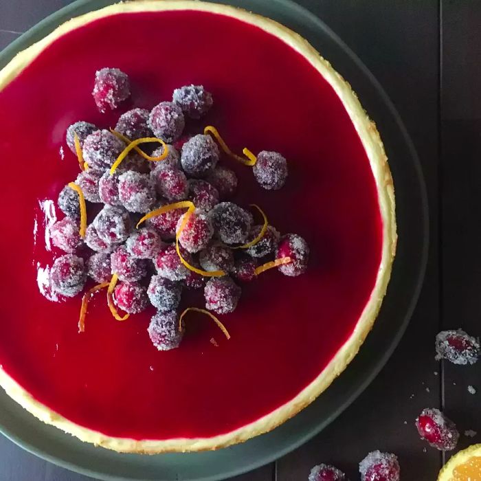 An overhead view of a Cheesecake topped with Cranberry Glaze and Sugared Cranberries.