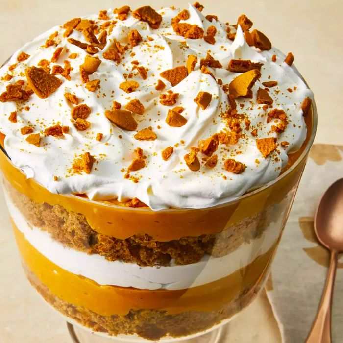 A close-up image showcasing the layers of pumpkin gingerbread trifle, with a large serving spoon placed beside it.