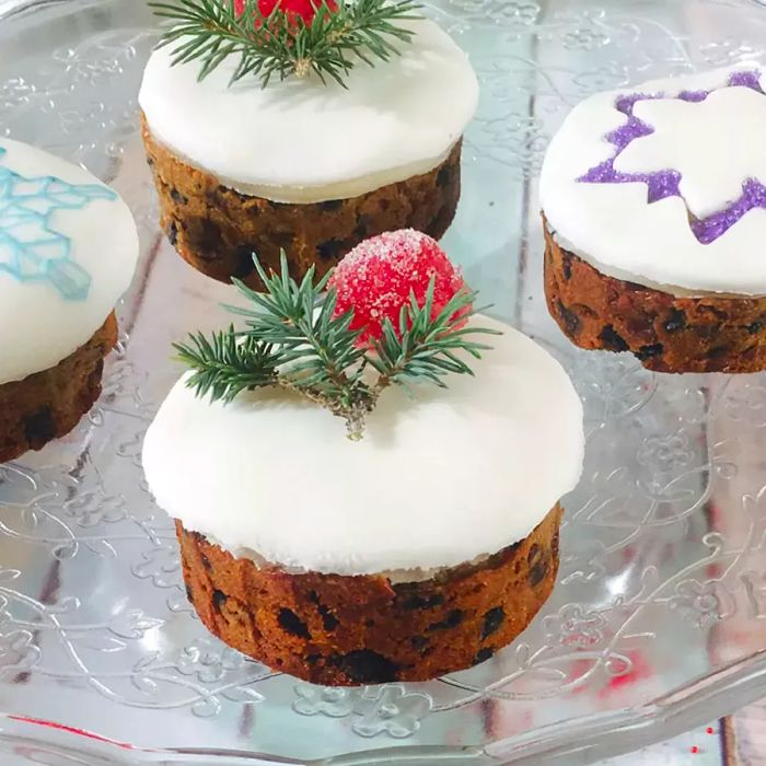 Cupcake-sized fruitcakes adorned with smooth royal icing and intricate snowflake designs.