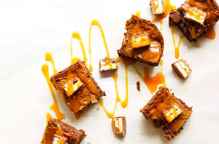 homemade brownies garnished with chopped candy bars and drizzled with caramel sauce