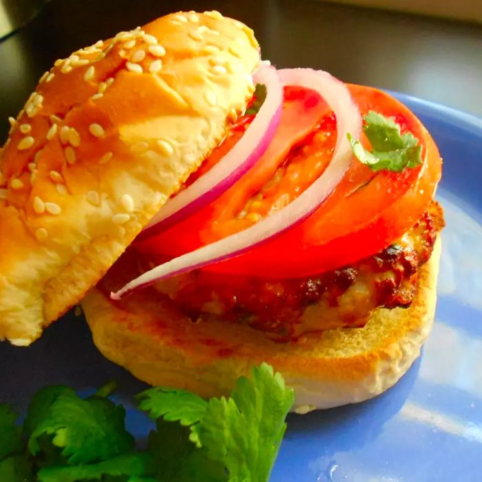 A turkey burger topped with tomato and red onion on a soft bun