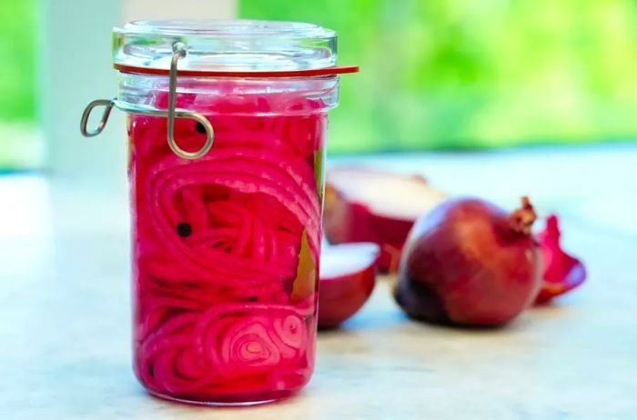 A close-up view of a glass jar filled with homemade pickled red onions.