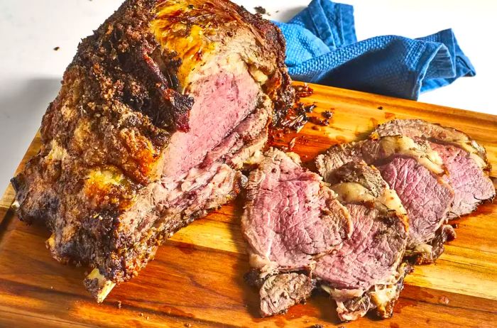 A whole prime rib displayed on a cutting board, with a few slices already cut.