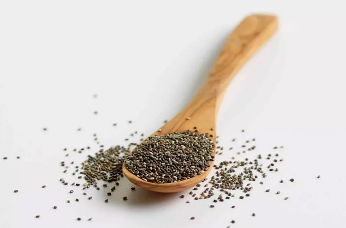 Chia seeds placed in a wooden spoon on a white background