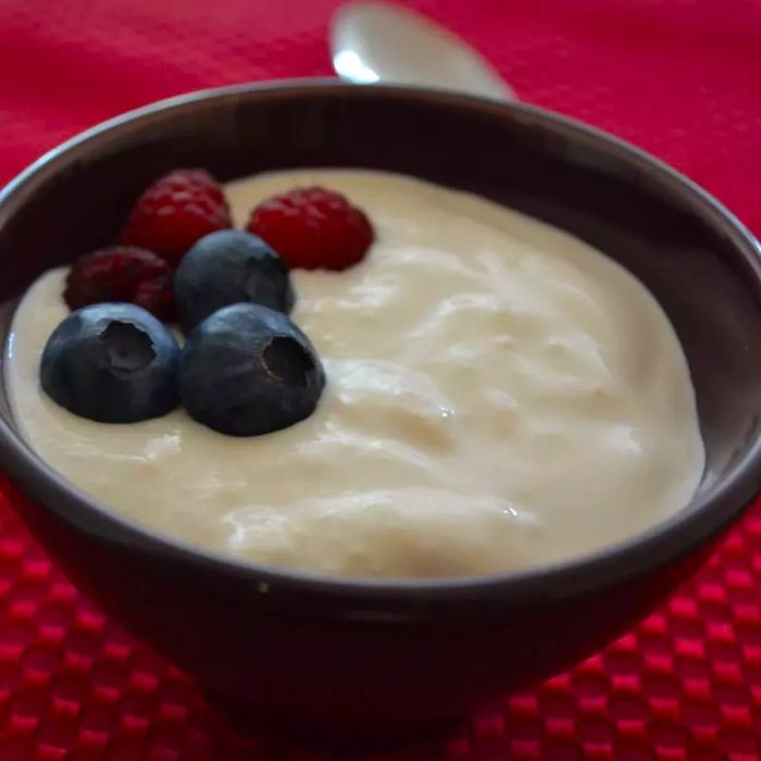 A bowl of creamy white yogurt topped with fresh blueberries and raspberries