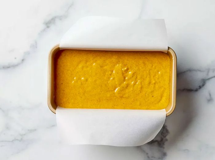 Pumpkin bread batter poured into a loaf pan, ready for baking.