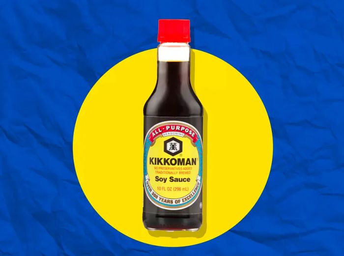 A bottle of Kikkoman soy sauce set against a blue and yellow backdrop