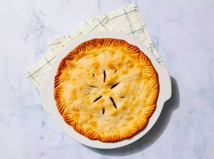 A fully baked meat pie resting on a kitchen towel.