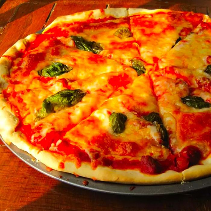 A close-up shot of a classic Pizza Margherita, served on a pizza plate atop a wooden surface.