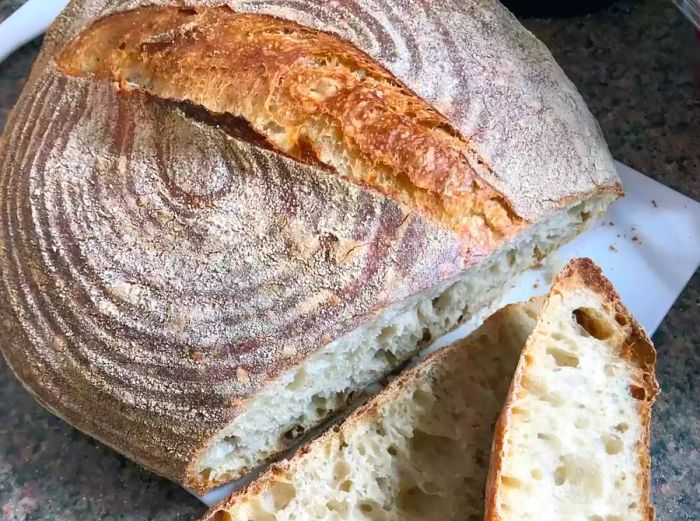 A top-down view of a golden-crusted boule with two slices cut, looking as perfect as a loaf from a bakery.