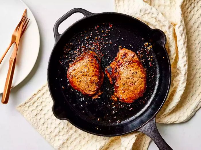 The perfectly seared steaks resting in a cast-iron skillet, ready to be served.