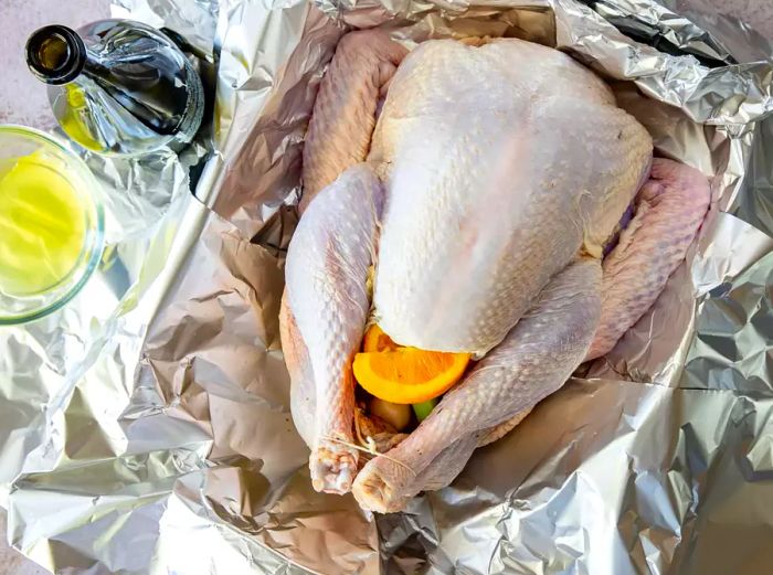 A raw turkey placed in a foil-lined roasting pan.