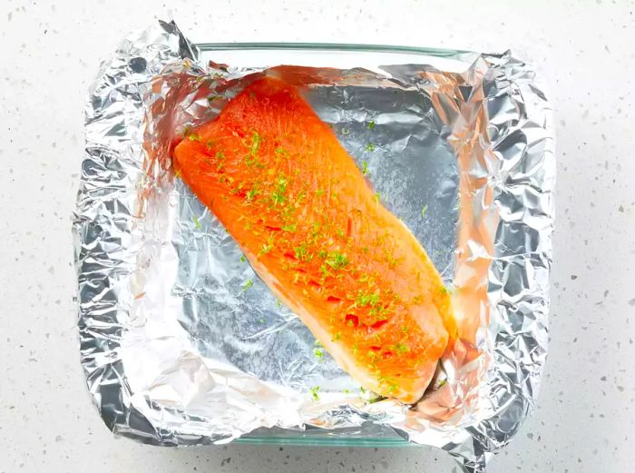 The Arctic Char is ready in the baking dish, seasoned with salt and topped with lime zest.