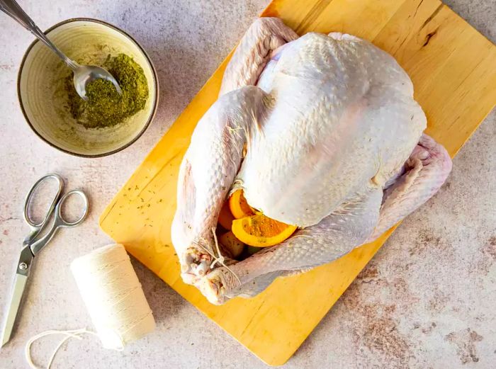 Raw turkey stuffed with seasonings and fresh citrus wedges.