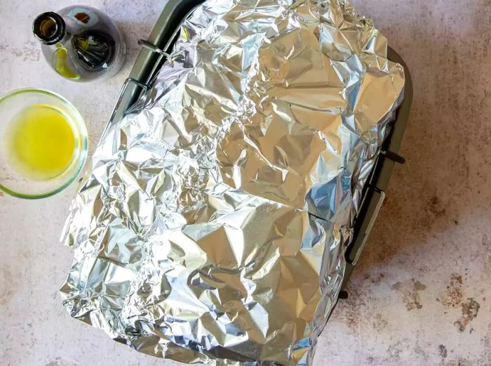 A turkey covered with foil, resting in a roasting pan.