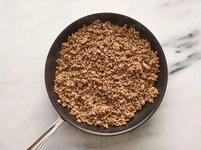 Ground beef cooking to a rich brown over medium heat.