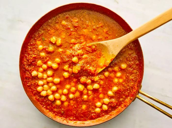 Stir chana masala in the skillet with a wooden spoon