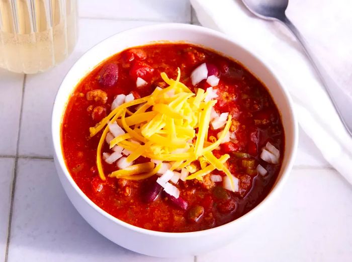 A bowl of homemade Wendy's chili, garnished with shredded cheese and onions