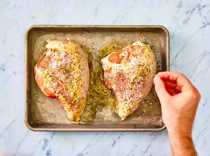 Chicken breasts seasoned with olive oil, garlic, salt, black pepper, rosemary, and basil.